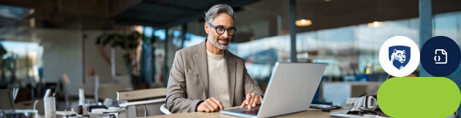 Individual sitting at a desk with a laptop in an office environment.