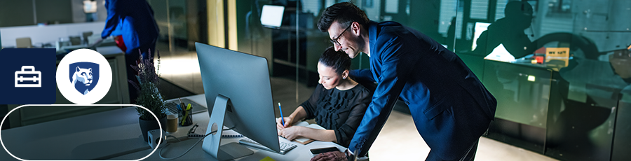 Two individuals in an office setting, collaborating at a computer desk. Benefits of the A+ Certification.